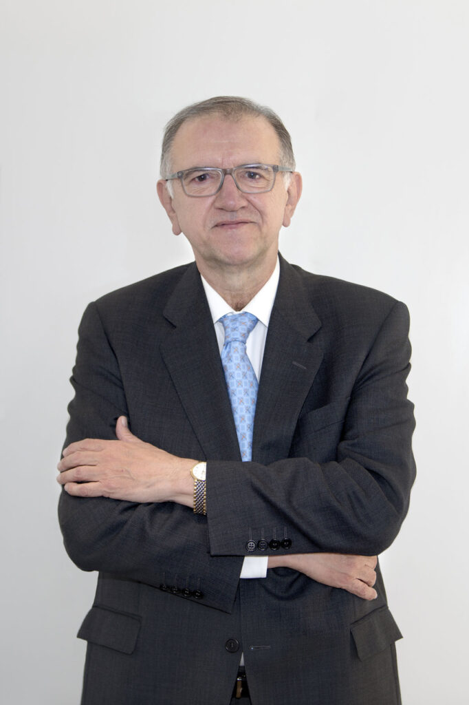 Hombre mediana edad con los ojos marrones y con gafas. En la foto aparece con los brazos cruzados sonriendo